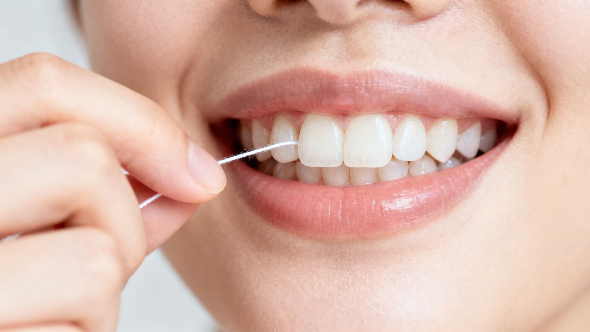 A close-up of a person flossing their white teeth, promoting good oral hygiene.